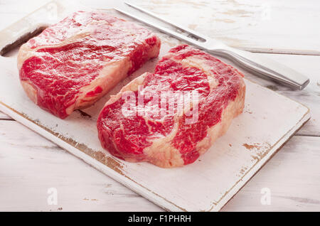 Crudo fresco Ribeye su un bianco tagliere di legno. Foto Stock