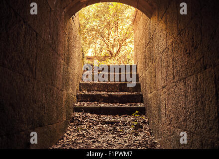 Uscita incandescente con scale da scuro abbandonato in calcestruzzo interni di tunnel, la calda tonalità del filtro di correzione Foto Stock
