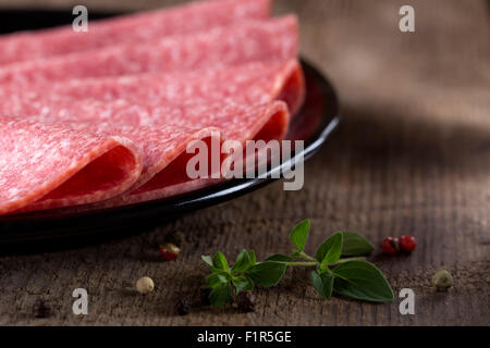 Salame sulla piastra nera in legno sfondo rustico Foto Stock