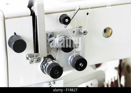 Close-up di una vecchia macchina da cucire con filo bianco Foto Stock