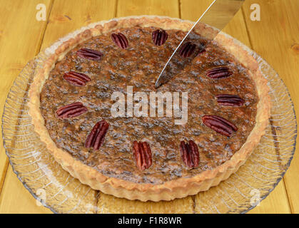 A partire da una fetta di pane appena sfornato, torta alle noci pecan su un tavolo di legno Foto Stock