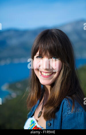 Una giovane ragazza bella bruna sorridente. Sfondo naturale Foto Stock