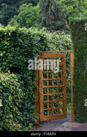 Legno garden gate mesh con pattern impostato tra le siepi Foto Stock