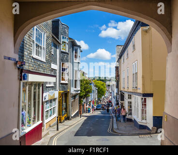 Negozi di Fore Street nel centro del paese visto dal High Street attraverso la porta est arch, Totnes, Devon, Inghilterra, Regno Unito Foto Stock