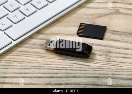 Close up di dati thumb drive e memoria flash card. Tastiera per computer in background sul desktop. Foto Stock