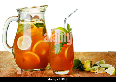 Tè freddo in la brocca e il vetro. Caraffa di freddo bevanda ghiacciata con limone e menta su un tavolo di legno su sfondo bianco. Foto Stock