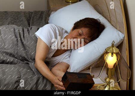 Senior donna che guarda la sveglia durante la notte. Concetto di insonnia. Foto Stock