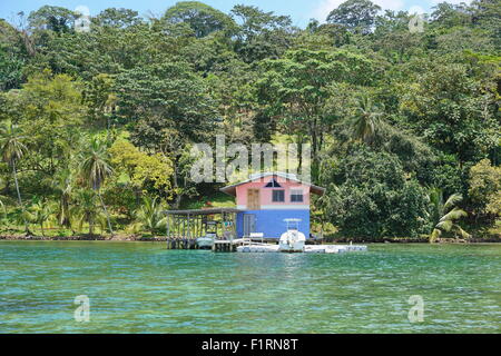 Casa sul mare con imbarcazioni al dock e la lussureggiante vegetazione tropicale sulla Costa Caraibica di Panama, America Centrale Foto Stock