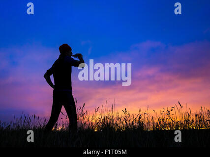 Cowpen Bewley parco boschivo, Billingham, Regno Unito. Il 7 settembre, 2015. Meteo: jogging sulla collina nel parco boschivo stagliano glow da Teesside's industrial skyline di pre alba luce il lunedì mattina. Credito: Alan Dawson News/Alamy Live News Foto Stock