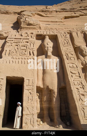 Uomo locale al tempio ingresso, Ramses II statua sulla destra, Hathor Tempio della Regina Nefertari, Abu Simbel, UNESCO, Egitto Foto Stock