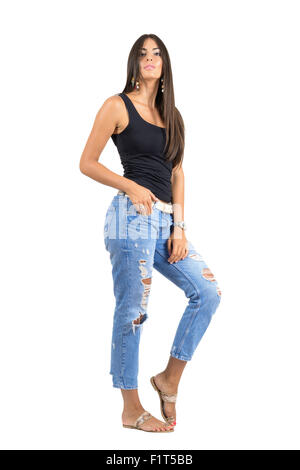 Giovane donna informale in jeans strappati in posa a telecamera. Corpo pieno lunghezza ritratto isolato su bianco di sfondo per studio. Foto Stock