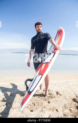 Surfista maschio sulla spiaggia Foto Stock
