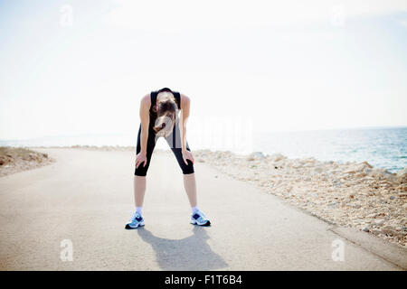 Donna in abbigliamento sportivo in piedi sul percorso fronte mare Foto Stock