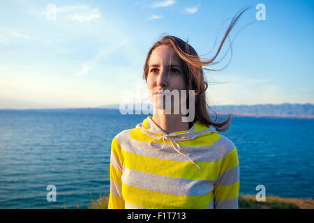 Donna capelli soffiando nel vento a mare Foto Stock