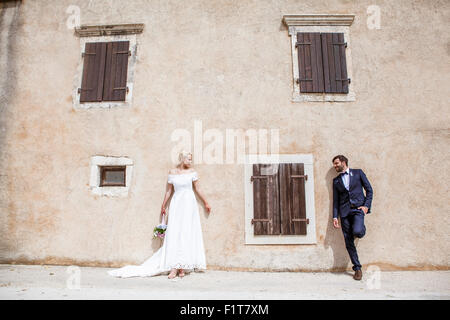 Sposa e lo sposo in piedi di fronte a muro di casa Foto Stock