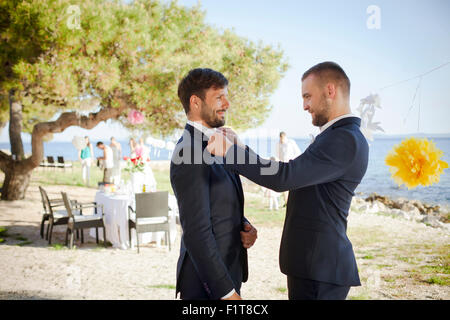 Amico regolando il filtro bow tie di groom sulla parte Foto Stock