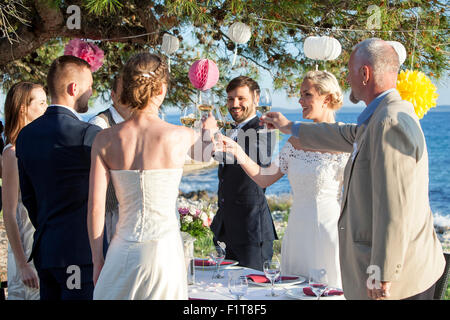 Bere champagne al ricevimento di nozze sulla spiaggia Foto Stock