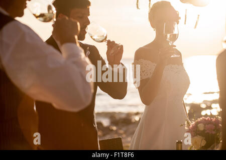 Bere champagne al ricevimento di nozze sulla spiaggia Foto Stock