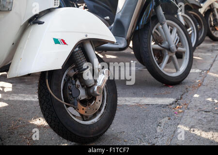 Ischia, Italia - 15 agosto 2015: Classico stile vecchia Vespa scooter sta parcheggiato su una strada, frammento con ruote anteriori Foto Stock