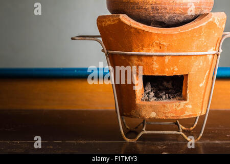 Carbone di legna e pentole di creta su un di legno Foto Stock