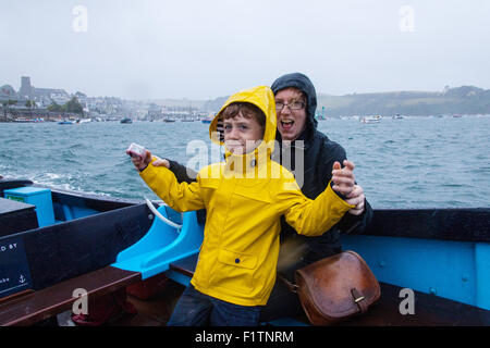 Madre e figlio (6 anni) sotto la pioggia sul traghetto Salcombe passeggeri tra East Portlemouth spiaggia e Salcombe, Devon, Inghilterra, Regno Unito. Foto Stock