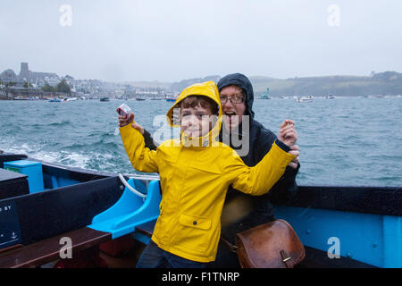 Madre e figlio (6 anni) sotto la pioggia sul traghetto Salcombe passeggeri tra East Portlemouth spiaggia e Salcombe, Devon, Inghilterra, Regno Unito. Foto Stock