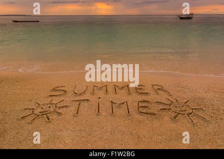 Nella foto una spiaggia al tramonto con le parole sulla sabbia 'Summer ora' . Foto Stock