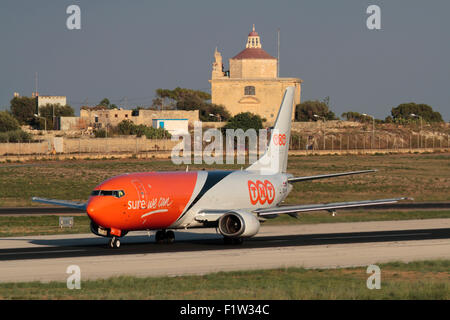 TNT Airways Boeing 737-400 cargo aereo decolla da Malta, con Ta' Loretu cappella, Gugja, in background Foto Stock