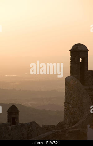 Torrette sul castello di Marvao stand in silhouette oltre l'Alentejo campagna al tramonto. Marvao, Portogallo. Luglio 17, 2015. Foto Stock