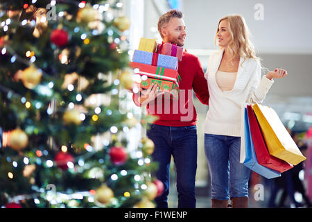 Affettuosa giovane portando regali di Natale mentre lo shopping nel centro commerciale Foto Stock