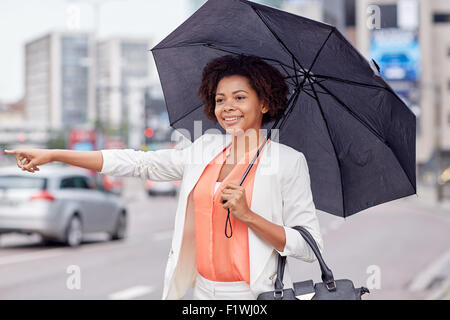 Felice donna africana con ombrello cattura di taxi Foto Stock