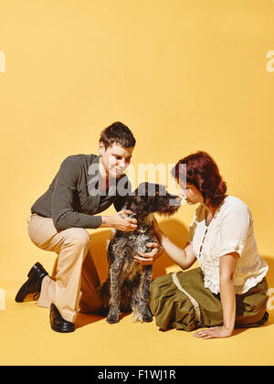 Giovane e cane insieme, 70's guardare tema, sfondo giallo Foto Stock