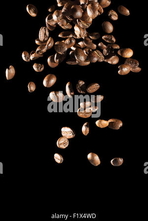 La caduta di chicchi di caffè su sfondo nero. Foto Stock