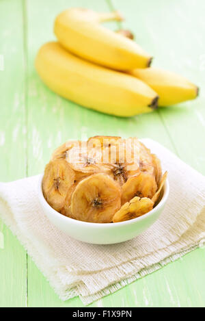 Banana chips in bianco ciotola e banane fresche Foto Stock