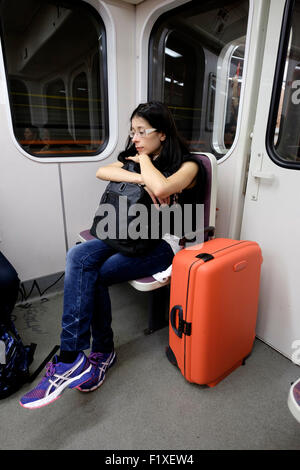 Giovane donna con una valigia rossa dormire in un treno della metropolitana di Praga, Repubblica Ceca, Europa Foto Stock