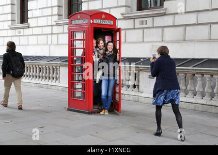 Un gruppo di famiglia di turisti squeeze in un tradizionale rosso English telefono box o chiosco per agguantare una foto ricordo della loro visita a Londra nel Regno Unito Foto Stock
