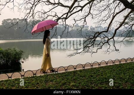 Il Vietnam, Hanoi, la città vecchia, il lago Hoan Kiem, donna in abito tradizionale Ao dai Foto Stock