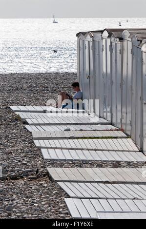 Francia, Seine Maritime, Le Havre, spiaggia capanne, giovane donna lettura Foto Stock