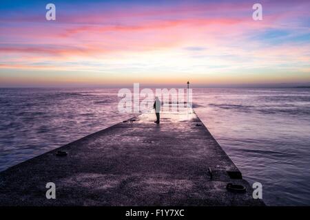 Francia, Finisterre, Fouesnant, Pointe de Mousterlin, pescatore sul molo al tramonto Foto Stock