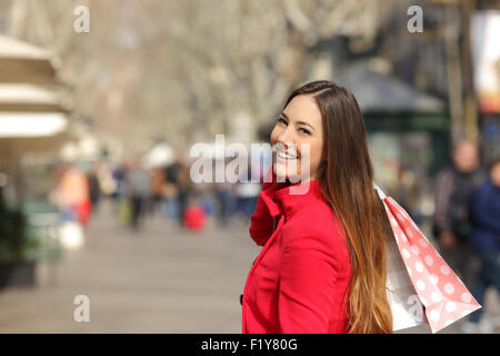 Happy shopper donna passeggiate e shopping in strada in inverno i sacchetti di contenimento Foto Stock