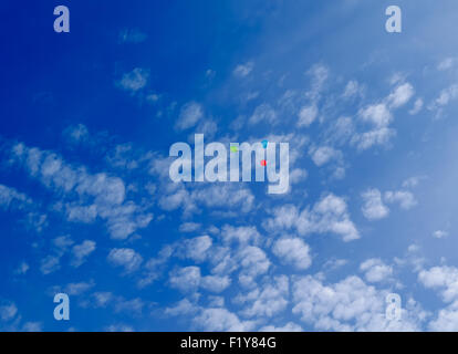 Tre multi-di palloncini colorati volare (hover) nel cielo blu con nuvole Foto Stock