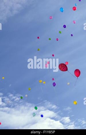 Molti di palloncini colorati volare (hover) nel cielo blu con nuvole Foto Stock