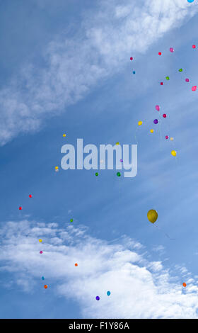 Molti di palloncini colorati volare (hover) nel cielo blu con nuvole Foto Stock