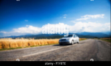 Sfocare lo sfondo con auto sulla strada rurale Foto Stock