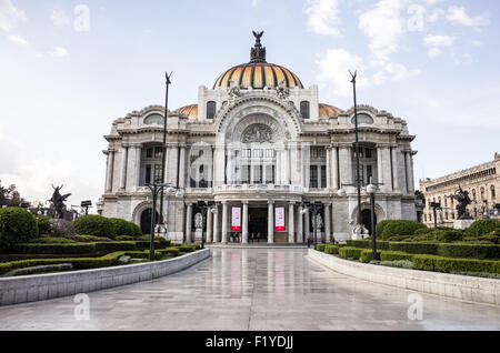 Facciata e cupola del Palacio de Bellas Artes a Città del Messico | CITTÀ DEL MESSICO, Messico — Il Palacio de Bellas Artes mostra la sua facciata in marmo bianco di Carrara e la cupola ricoperta di piastrelle dorate dall'esplanade dell'Alameda Central, con uno dei gruppi scultorei di Pegaso di Agustí Querol Subirats visibile a sinistra. Le piastrelle ceramiche della cupola passano attraverso circa sei toni dorati fino arancioni su costoloni rivestiti di rame, ed è sormontata dalla corona di bronzo dello scultore ungherese Géza Maróti, composta da quattro figure alate che circondano l'aquila azteca che divora un serpente, emblema nazionale del Messico. Foto Stock