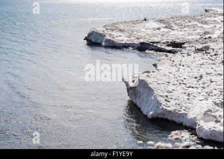 Bordo di bianco sporco e marrone floes di ghiaccio e neve in acqua durante le ore diurne, con parti parzialmente ghiaccio sciolto in acqua. Foto Stock