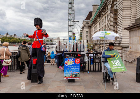 Un uomo vestito in uniforme protezioni mani volantini e pone per fotografie con i turisti, Londra, Inghilterra Foto Stock