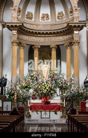 CITTÀ DEL MESSICO, Messico — Una statua di San Bernardo di Chiaravalle, circondata da fiori freschi, si trova al centro dell'altare maggiore neoclassico nell'Iglesia de San Bernardo. Il fondatore cistercense del XII secolo e Dottore della Chiesa è onorato in questa chiesa del XVII secolo vicino allo Zocalo di città del Messico. La decorazione combina la tradizionale statuaria cattolica con elaborate composizioni floreali. Questa opera religiosa rappresenta l'omonimo santo della chiesa e dimostra le continue pratiche devozionali. Foto Stock