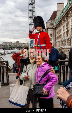 Un uomo vestito in uniforme protezioni mani volantini e pone per fotografie con i turisti, Londra, Inghilterra Foto Stock