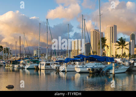 Tramonto a Ala Wai Harbour con Harbour e yacht in primo piano e alto hotel in background Foto Stock